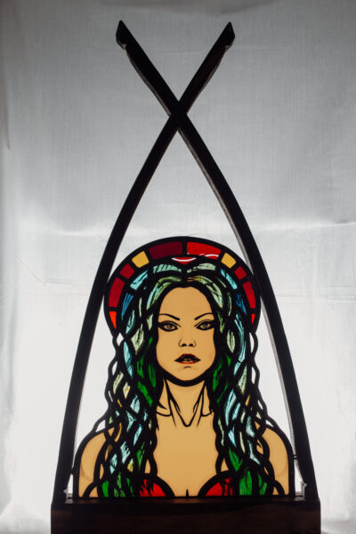 Vibrant stained glass artwork portraying Peisinoe, the siren of the mind. Richly colored glass pieces arranged intricately, capturing her ethereal beauty and the power of her enchanting presence.